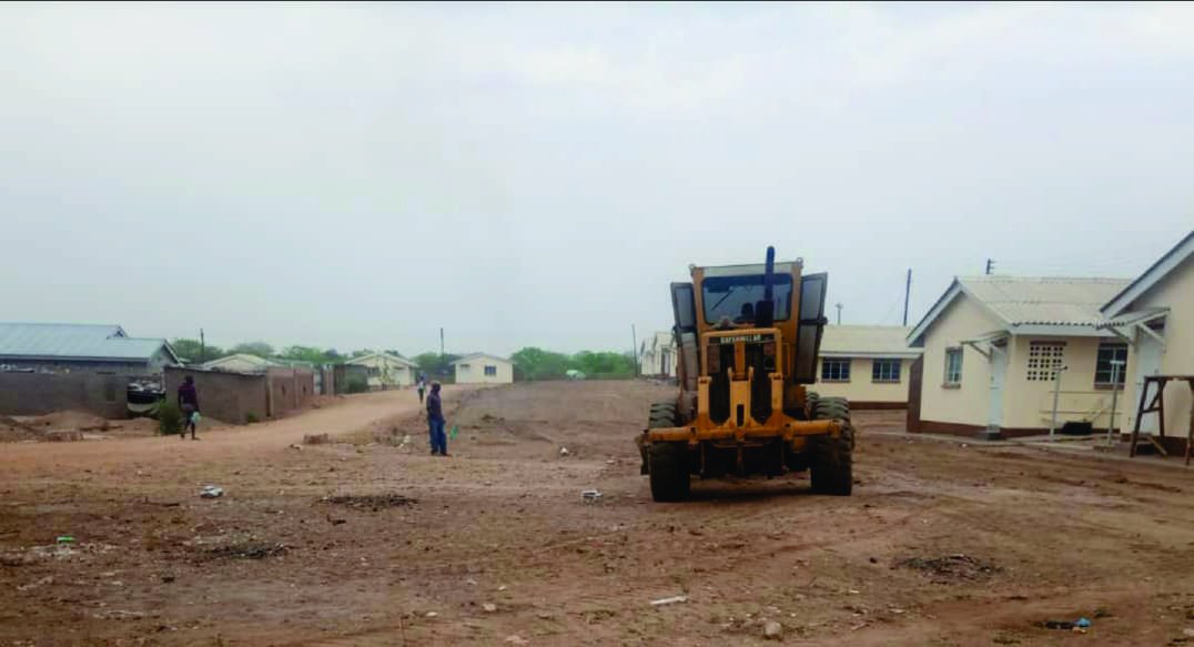 Grader levelling an access road between completed houses.